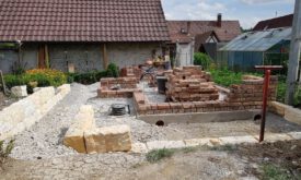 Während die Mauerarbeiten fortschreiten, entsteht nebenher eine Natursteinmauer aus Sandstein.